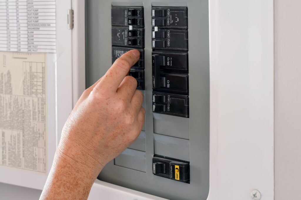 Woman's hand operating a residential electrical panel inside a home. Concept of household electricity, power control, safety, maintenance, and home utilities in a domestic ... See More