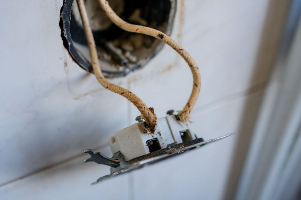 Close-up of old-fashioned cloth insulated electrical wiring in a wall socket. Perfect for showing fire hazards, outdated electrical standards, and home renovation in vintage ... See More